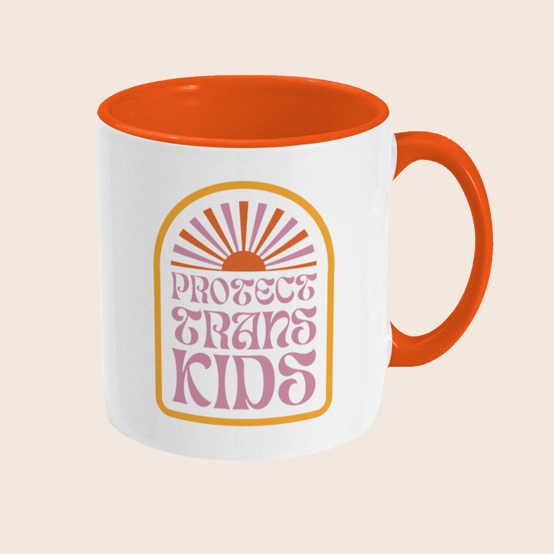 Right-side view of a white ceramic mug with an orange handle and interior. The visible part of the design features a rising sun and partial retro lettering in pink and orange, continuing the "Protect Trans Kids" message.