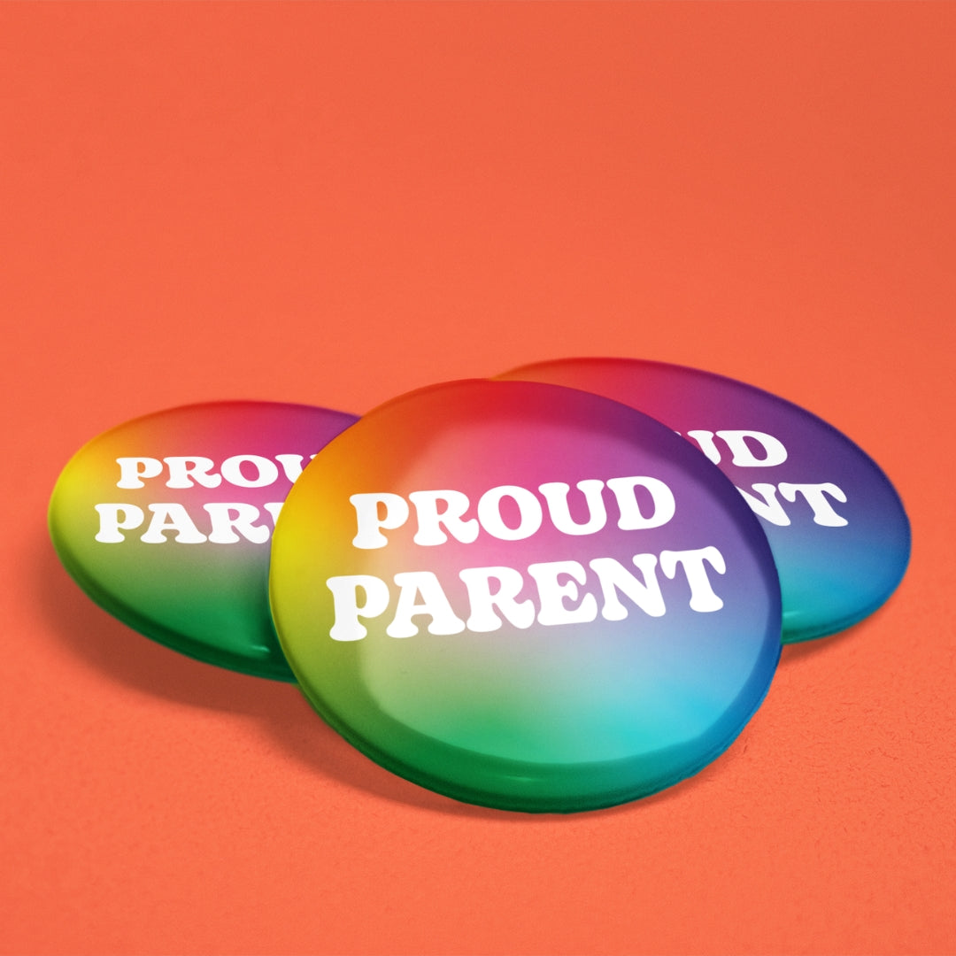 Three 38mm Proud Parent rainbow badges with glossy finish displayed on an orange background.