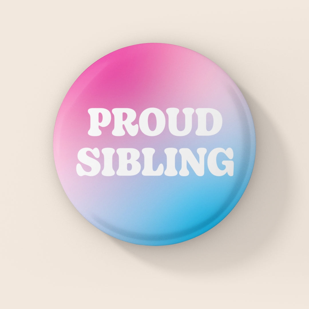38mm Proud Sibling badge featuring white text on a pink, white and blue transgender flag gradient background.