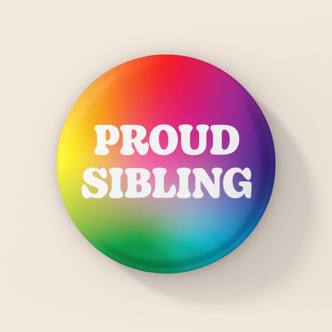 38mm rainbow gradient badge reading “Proud Sibling” in white retro lettering on a glossy finish.