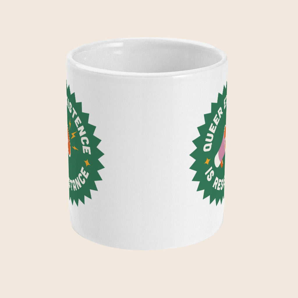 A white ceramic mug shown with the handle facing away, displaying part of a bold green starburst graphic with a visible pink and orange megaphone. The image shows how the graphic is repeated on each side of the mug. The background is a soft beige.