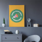 A Queer Existence is Resistance print hanging on a grey wall above a minimalist chest of drawers with a vintage typewriter and books