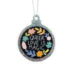 A silver glitter bauble against a white background featuring the text Queer Love is Magic and hand drawn illustrations of flowers in rainbow colours. It is held up by a silver string.