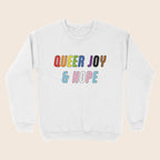 White sweatshirt with colourful “Queer Joy & Hope” text across the chest in rainbow and trans Pride-inspired colours.