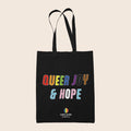 Black tote bag featuring colourful text reading “Queer Joy & Hope” in rainbow and trans Pride-inspired colours.