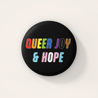 Black round 38mm badge featuring the words "Queer Joy & Hope" in bold, multicoloured lettering inspired by the rainbow and transgender Pride flags.