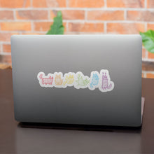 Load image into Gallery viewer, A laptop with a line of stickers featuring mummy-wrapped cats, each one coloured in a different shade of the rainbow, symbolising LGBTQ+ pride.