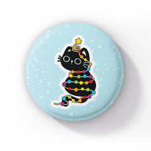 Load image into Gallery viewer, A black cat wrapped in rainbow-coloured string lights, with a star atop its head, sitting playfully on a light blue background with snowflakes.