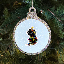 Load image into Gallery viewer, A sparkly Christmas bauble with a black cat tangled in rainbow-coloured fairy lights. The cat sits with a star on its head, looking adorable against a snowy background, hanging on a Christmas tree.