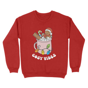 Fire Red sweatshirt featuring retro text reading 'cosy vibes'. The image shows a mug of hot chocolate with marshmallows and a gingerbread man wearing a Santa hat. A candy cane in the mug and lights around the mug are the colours of the rainbow pride flag.