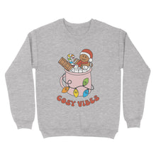 Load image into Gallery viewer, Heather Grey sweatshirt featuring retro text reading &#39;cosy vibes&#39;. The image shows a mug of hot chocolate with marshmallows and a gingerbread man wearing a Santa hat. A candy cane in the mug and lights around the mug are the colours of the rainbow pride flag.
