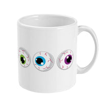 Load image into Gallery viewer, The right side of a white ceramic mug showing a series of cartoon eyeballs with irises in red, orange, and yellow. The design represents the full spectrum of the rainbow flag colours, complete with red veins on the eyeballs for a playful and eerie look.