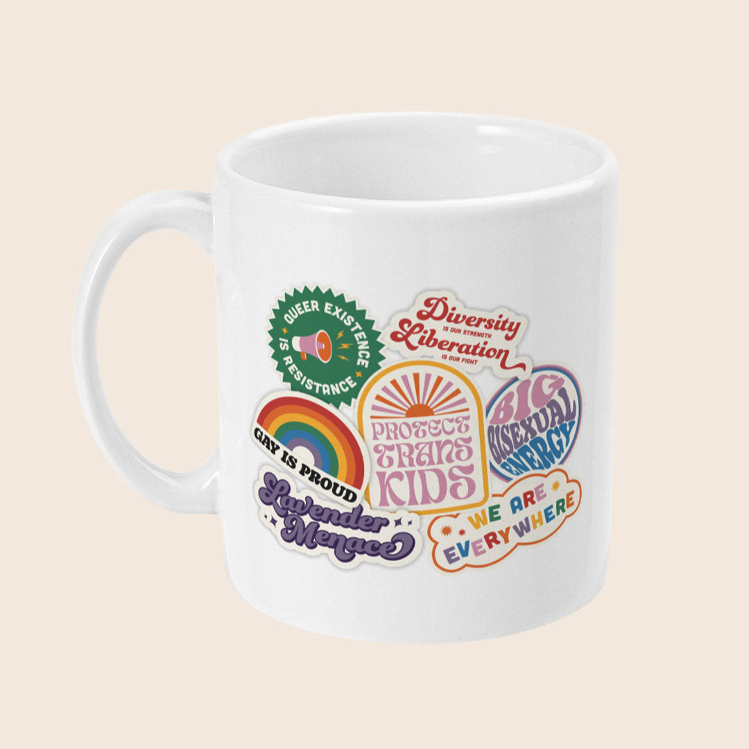 White ceramic mug covered in colourful retro-style stickers, including slogans like “Protect Trans Kids,” “Gay Is Proud,” “Lavender Menace,” “Queer Existence Is Resistance,” “Big Bisexual Energy,” “We Are Everywhere,” and “Diversity is Our Strength, Liberation is Our Fight.”