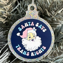 Load image into Gallery viewer, Close up of a white Christmas tree displaying a silver glitter bauble featuring the text Santa Says Trans Rights and a illustration of Santa Claus