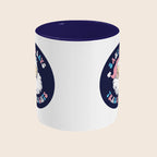 A white ceramic mug with a dark navy interior. The design features a vintage-style Santa Claus illustration wearing a pink hat, with the phrase “Santa Says Trans Rights” in pastel blue and pink letters surrounding the image.