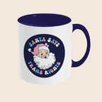 A white ceramic mug with a navy handle and interior. The front features a cheerful illustration of Santa Claus with a pink hat, surrounded by pastel lettering that reads “Santa Says Trans Rights.”