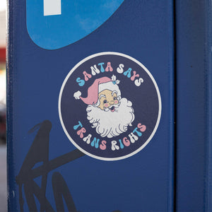 Santa Says Trans Rights Sticker stuck to a blue metal parking metre