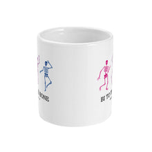 Load image into Gallery viewer, A white ceramic coffee mug with handle facing away from view. The mug shows three dancing skeletons in the colours of the bisexual flag and the slogan &#39;Bi To The Bone&#39;
