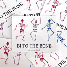 Load image into Gallery viewer, A pile of gloss stickers. Each sticker features three dancing skeletons in the colours of the bisexual flag and the slogan &#39;Bi To The Bone&#39;