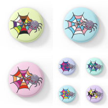 Load image into Gallery viewer, A collection of circular badges, each featuring a cute grey spider with pink eyes on a web coloured in various pride flag colours, including asexual, bisexual, gay, lesbian, non-binary, pansexual, rainbow, and transgender pride flags. Each badge has a different pastel background colour.