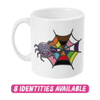 A white ceramic mug featuring a cute cartoon spider next to a colourful spider web that represents the rainbow flag. The text "8 IDENTITIES AVAILABLE" is displayed in bold, dripping pink letters below the mug, highlighting the variety of designs available in this collection.