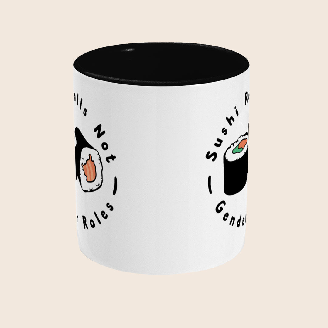 A white ceramic mug with a black interior. The mug design features two sushi rolls and the phrase “Sushi Rolls Not Gender Roles” in black text, wrapping around the mug.