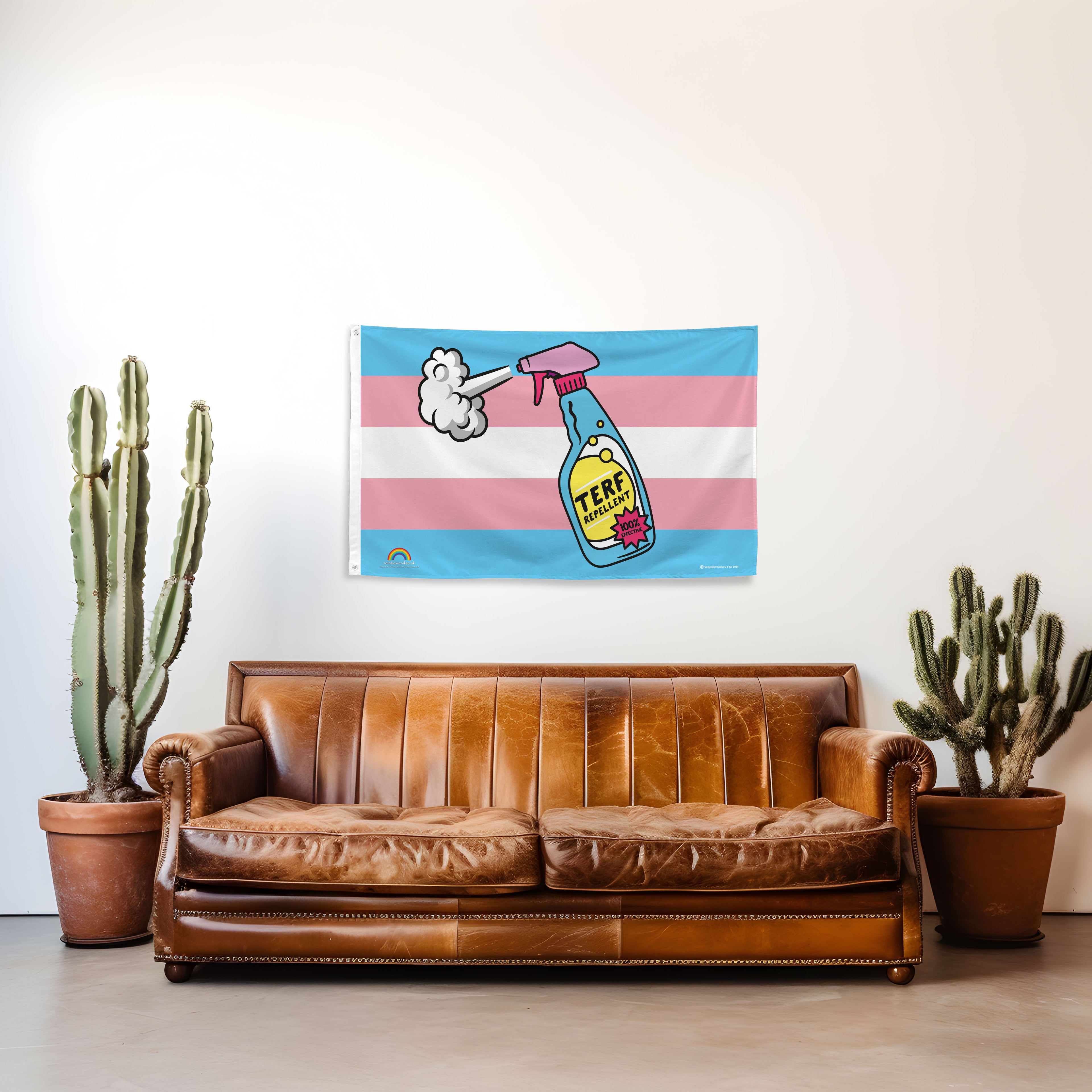 Brown leather sofa in a room with a Trans Pride flag featuring a spray bottle of TERF Repellent on the wall, potted cacti on either side.