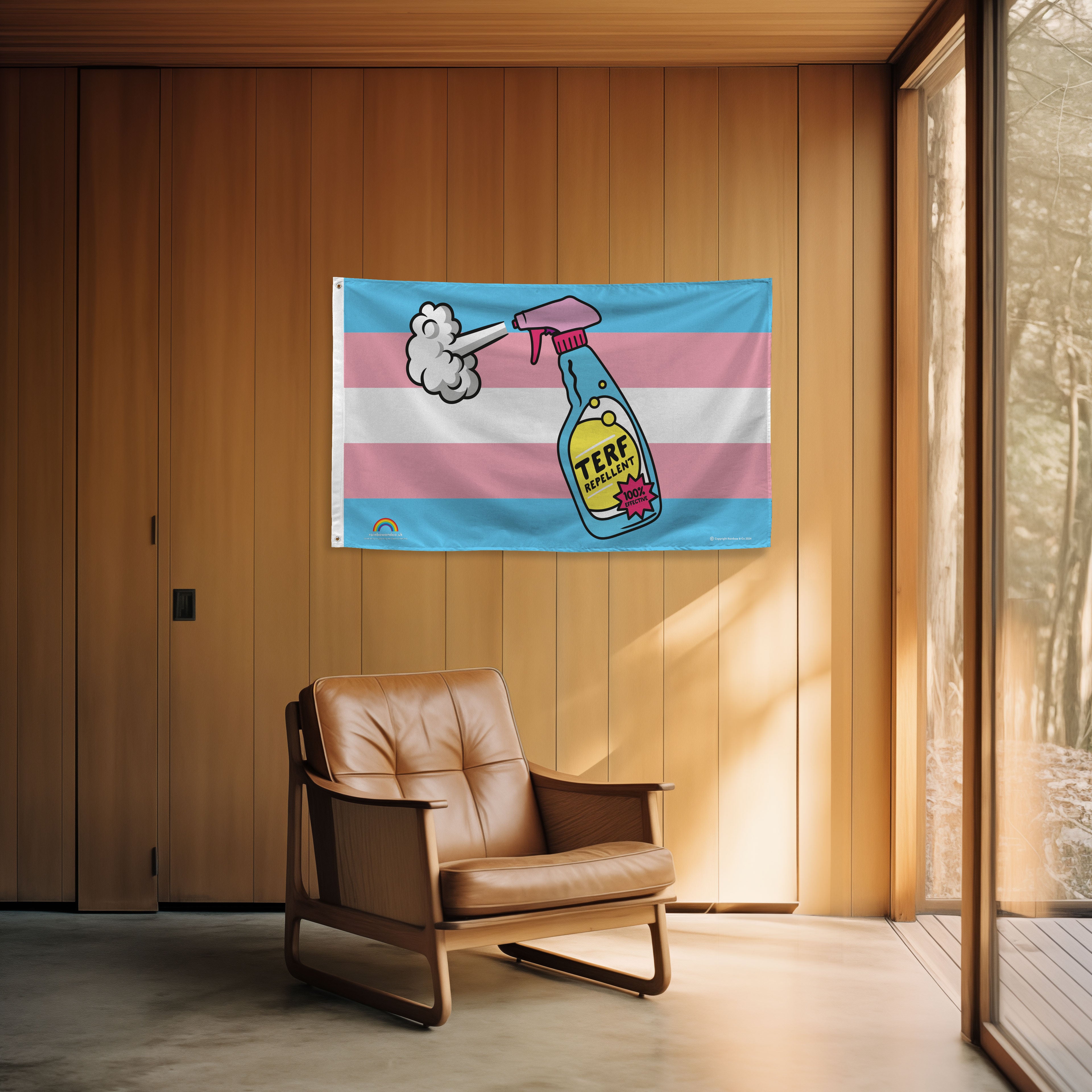 Transgender pride flag with a cartoon design of a spray bottle labeled 'TERF Repellent' in a room with wooden walls and a brown leather chair.