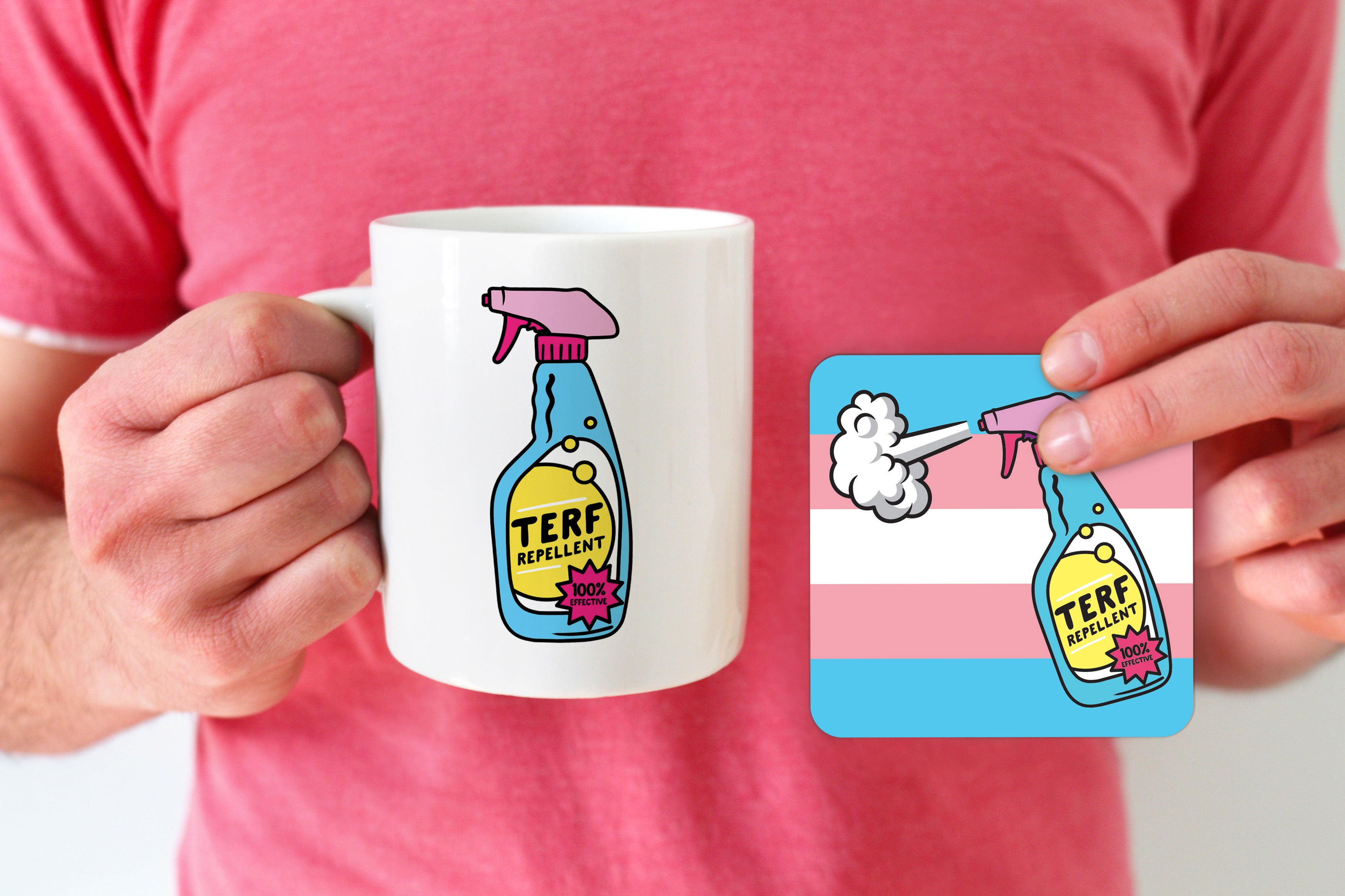 A white ceramic mug featuring a colourful "TERF Repellent" design with a spray bottle, alongside a matching square coaster with the same design over a transgender pride flag background. The mug is held by a person wearing a pink shirt.