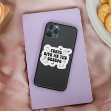 Load image into Gallery viewer, A white sticker with the text &quot;TERFs Give Me The Creeps&quot; in black, surrounded by small ghost and bat illustrations, is applied to the back of a black smartphone case. The phone rests on a light purple notebook placed on a soft pink fabric surface next to a lit candle and a plate of crackers.