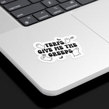 Load image into Gallery viewer, A die-cut sticker with the phrase &quot;TERFs GIVE ME THE CREEPS&quot; in bold, spooky font is placed on the lower corner of a silver laptop. The sticker is designed in black and white with cartoon ghosts and small bats surrounding the text, adding to its Halloween-inspired theme. The laptop rests on a black background, emphasising the sticker&#39;s design.