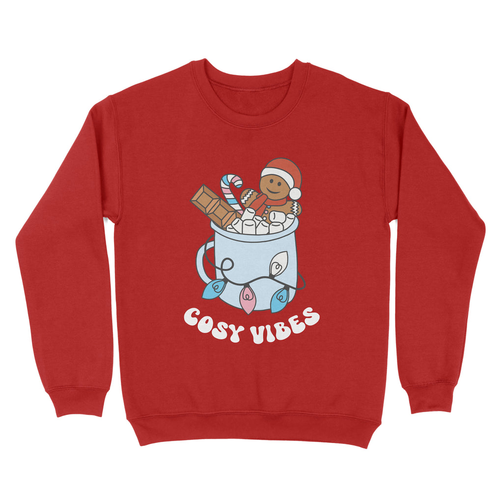 Fire Red sweatshirt featuring retro text reading 'cosy vibes'. The image shows a mug of hot chocolate with marshmallows and a gingerbread man wearing a Santa hat. A candy cane in the mug and lights around the mug are the colours of the transgender pride flag.