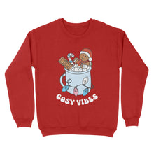 Load image into Gallery viewer, Fire Red sweatshirt featuring retro text reading &#39;cosy vibes&#39;. The image shows a mug of hot chocolate with marshmallows and a gingerbread man wearing a Santa hat. A candy cane in the mug and lights around the mug are the colours of the transgender pride flag.