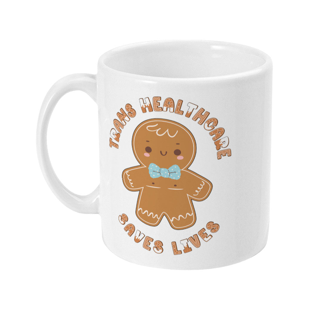 Front view of a white mug showcasing a gingerbread figure with a blue bow tie in the centre, surrounded by the phrase "Trans Healthcare Saves Lives" in a circular pattern.