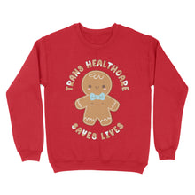 Load image into Gallery viewer, Fire red sweatshirt displaying a gingerbread person alongside the message &#39;Trans Healthcare Saves Lives&#39; in seasonal style.