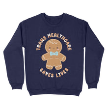 Load image into Gallery viewer, Oxford navy sweatshirt showcasing a gingerbread person with the words &#39;Trans Healthcare Saves Lives&#39; in a festive font.