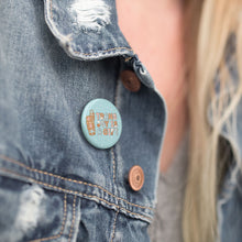 Load image into Gallery viewer, A close-up of a &quot;Trans Joy is a Gift&quot; badge pinned on a denim jacket, accentuating the badge against the rugged texture of the denim.