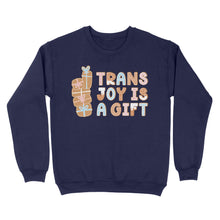 Load image into Gallery viewer, Oxford navy sweatshirt adorned with the phrase &#39;Trans Joy Is A Gift&#39; in a gingerbread-inspired design, flanked by a vertical stack of pastel-coloured presents.