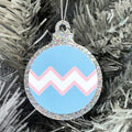 Close up of a white Christmas tree displaying a silver glitter bauble featuring a classic zig zag design in the colours of the transgender pride flag.