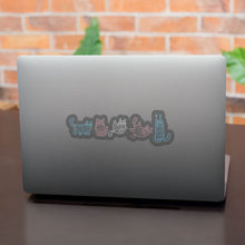 Load image into Gallery viewer, A laptop with stickers of mummy-wrapped cats in pastel blue, pink, and white, representing the transgender flag colours.