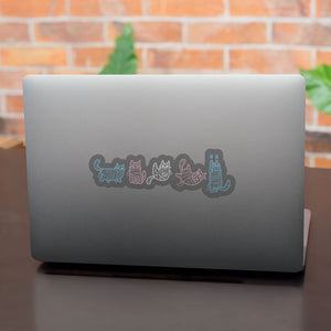 A laptop with stickers of mummy-wrapped cats in pastel blue, pink, and white, representing the transgender flag colours.