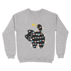 Heather grey sweatshirt with a playful black cat wrapped in Christmas lights inspired by the transgender pride flag, holding up its tail with a star decoration.