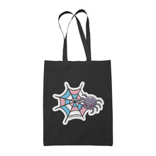 Load image into Gallery viewer, A black tote bag featuring a cute cartoon spider in front of a spider web coloured in the transgender pride flag colours: blue, pink, and white.