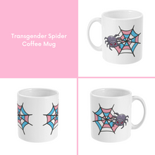 Load image into Gallery viewer, A composite image of a white coffee mug with a cartoon spider and spider web design in transgender pride flag colours. 