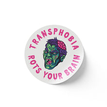 Load image into Gallery viewer, A round white sticker featuring a green zombie face with an exposed brain. The phrase &quot;Transphobia Rots Your Brain&quot; is printed in bright pink letters surrounding the graphic.