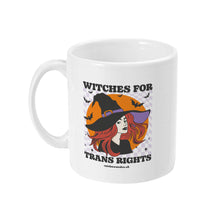 Load image into Gallery viewer, A white ceramic coffee mug with the handle on the left. The mug shows the slogan Witches for Trans Rights with an illustrated graphic of a witch with bats flying around her hat