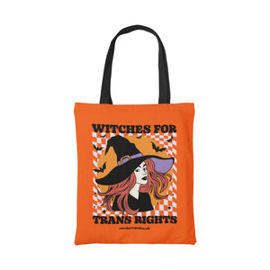 Orange cotton tote bag featuring the slogan Witches for Trans Rights with an illustrated graphic of a witch with bats flying around her hat