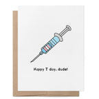 Happy T Day, Dude! greeting card featuring a syringe decorated in the colours of the transgender flag.