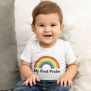 A young child with short brown hair wearing blue jeans and a white My First Pride t shirt from Rainbow & Co