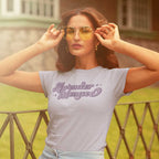 Retro style photo of a young woman wearing large vintage sunglasses and a lavender colours, 'Lavender Menace' crew neck shirt.